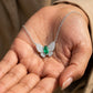 Real-life lifestyle hand view of a model holding a luxury marquise-cut emerald butterfly pendant necklace in her palm.