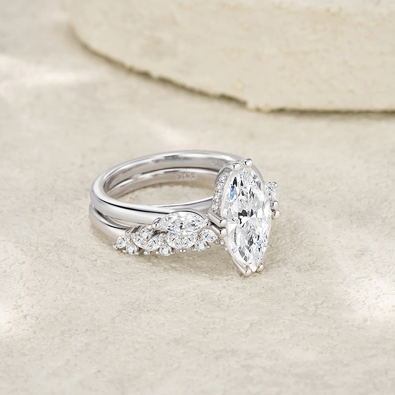 Angled view of marquise cut moissanite three stone engagement ring and matching band.