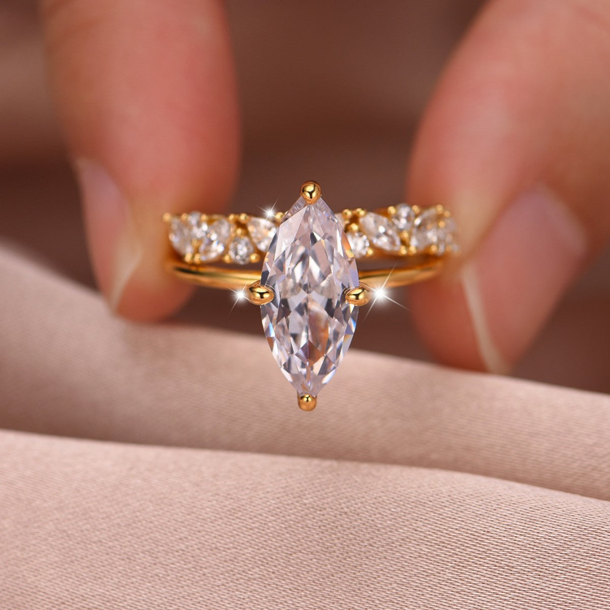 Close-up view of gold marquise cut solitaire ring with matching crown band held in hand.