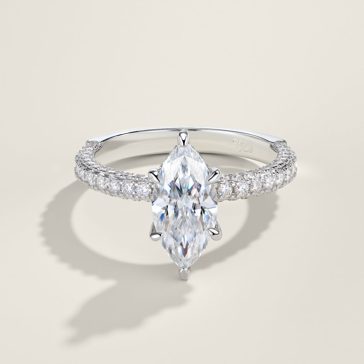 Silver marquise cut moissanite solitaire ring with pave shank standing on soft cream background.