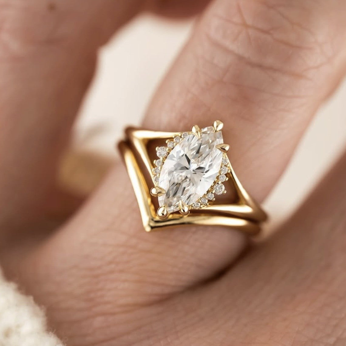 Top-down hand shot of model wearing gold marquise cut moissanite solitaire and wishbone chevron ring set.