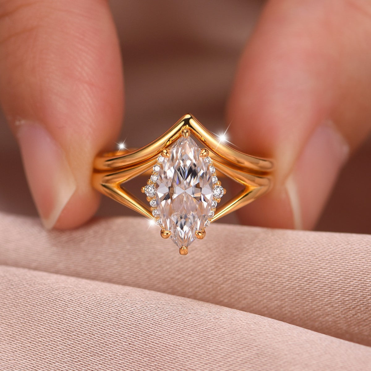 Close-up view of gold marquise cut solitaire ring with matching wishbone chevron band held in hand.
