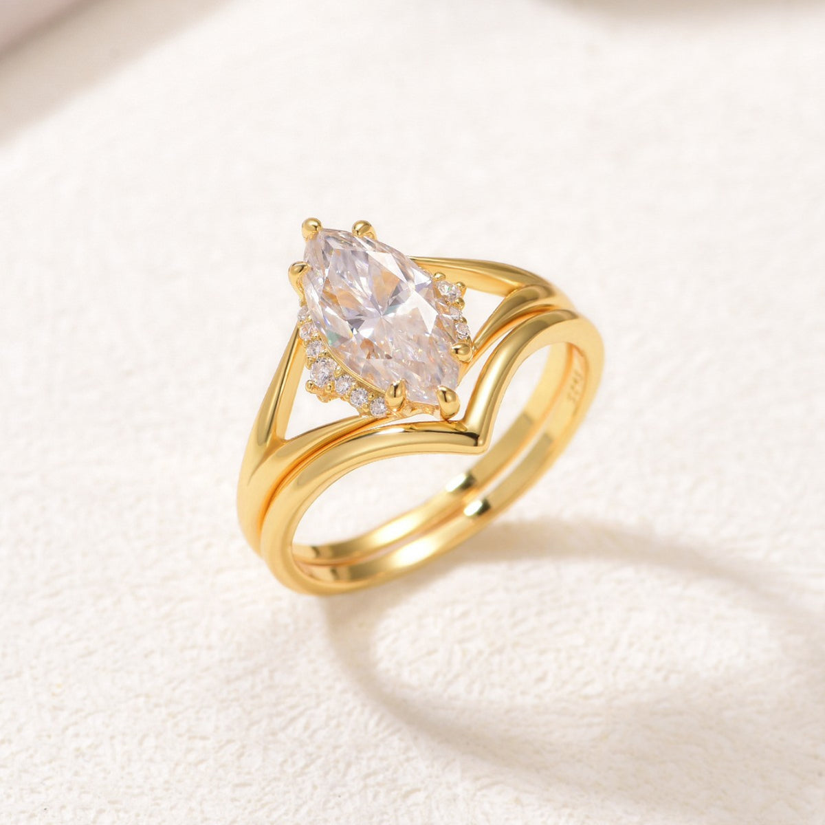 Perspective view of gold marquise moissanite solitaire and wishbone chevron band.