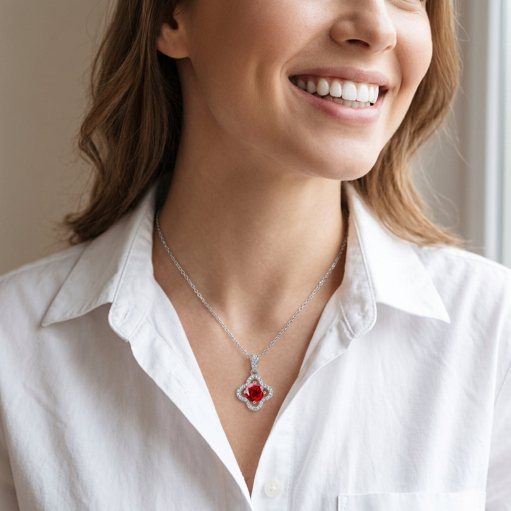 Editorial portrait view of a smiling model wearing a minimalist ruby clover motif pendant necklace with a crisp white shirt.