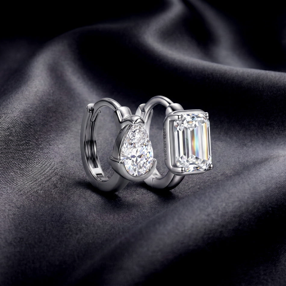 Perspective shot of asymmetric pear and emerald cut lab diamond bezel huggie hoop earrings.