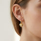 Gold heart-shaped earring worn by a person with a neutral background