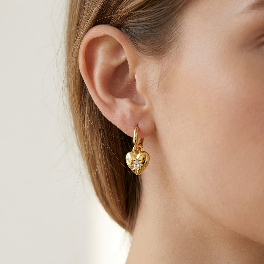 Gold heart-shaped earring worn by a person with a neutral background
