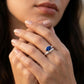 Close-up editorial lifestyle portrait of a model showcasing a modern marquise-cut sapphire statement ring on her hand.