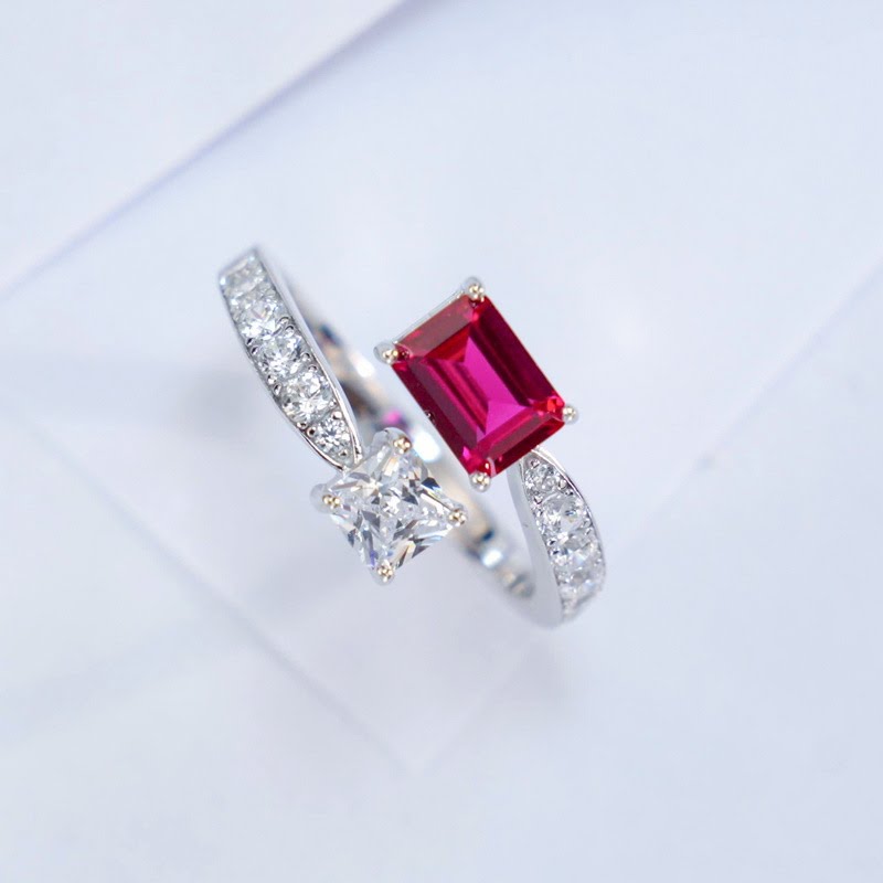 Three-quarter studio product profile focusing on the open-band architecture of a modern ruby and white sapphire Toi et Moi ring.