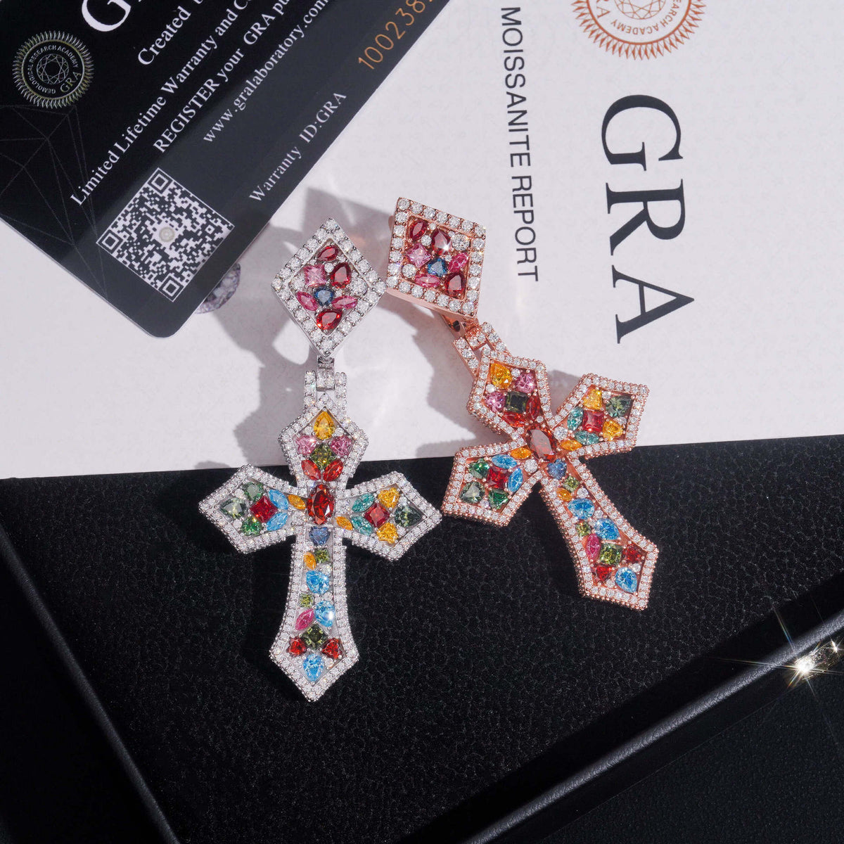 Rose gold and silver S925 multi-color moissanite cross pendants leaning against GRA certificate card