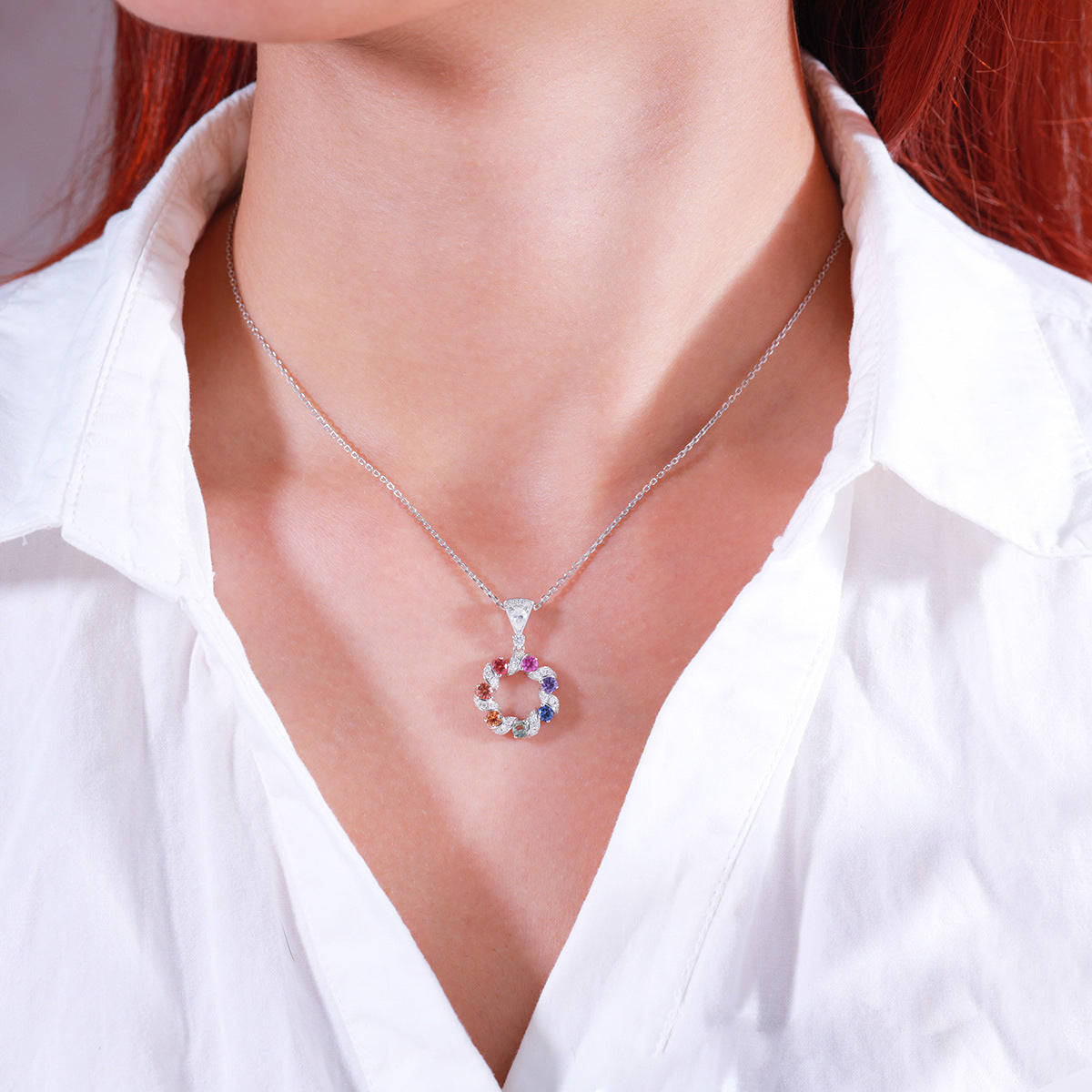 Model wearing multi-color sapphire wreath circle pendant necklace with white unbuttoned shirt.