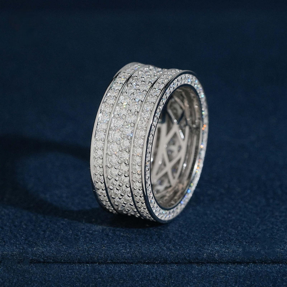 Multi row micro pave moissanite wide eternity band ring in sterling silver resting on dark blue box