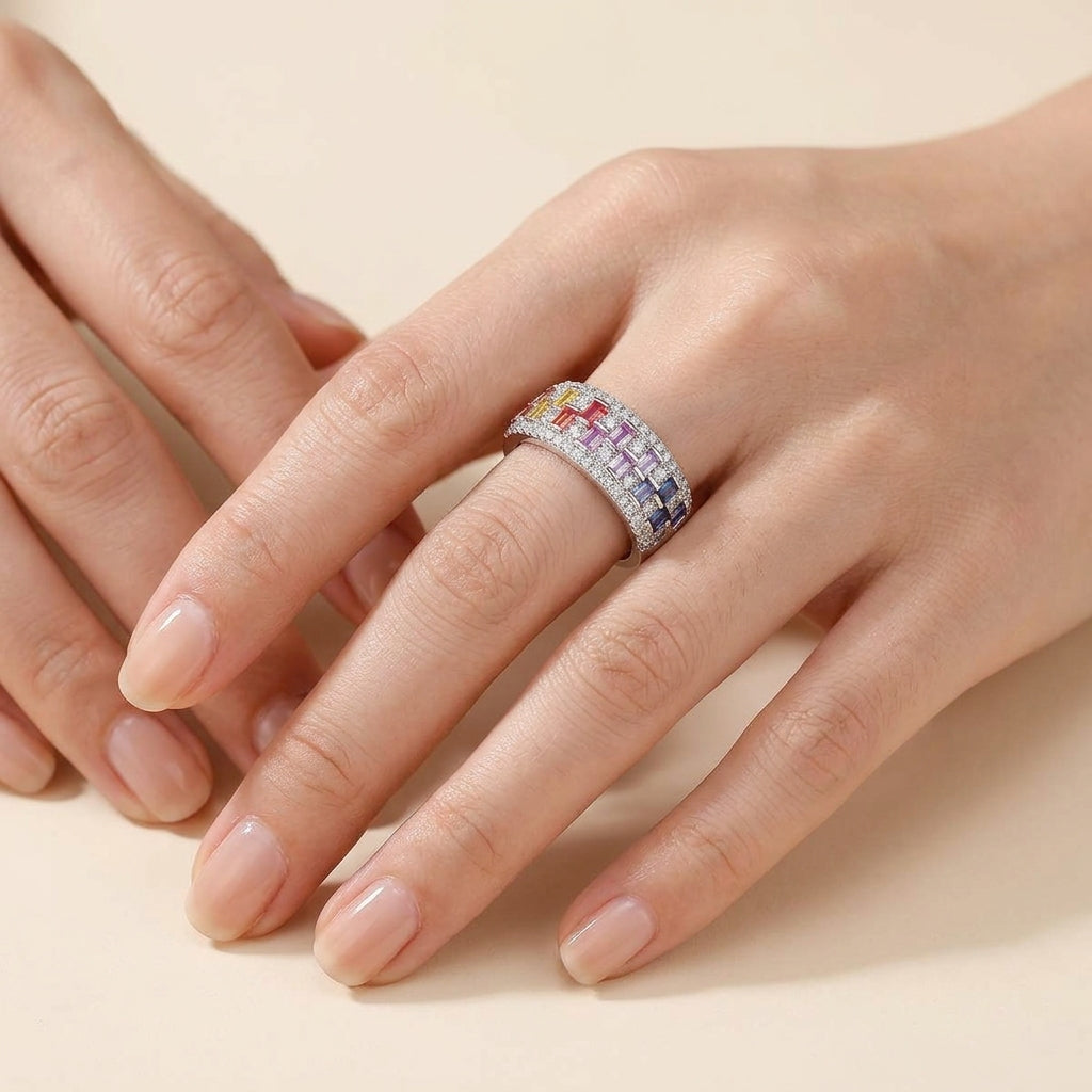 Close up view of woman wearing multicolor baguette gemstone and moissanite wide band ring on hand