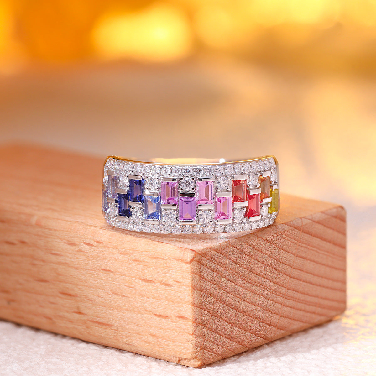 Side view of multicolor baguette gemstone and moissanite wide band ring displayed on wooden block