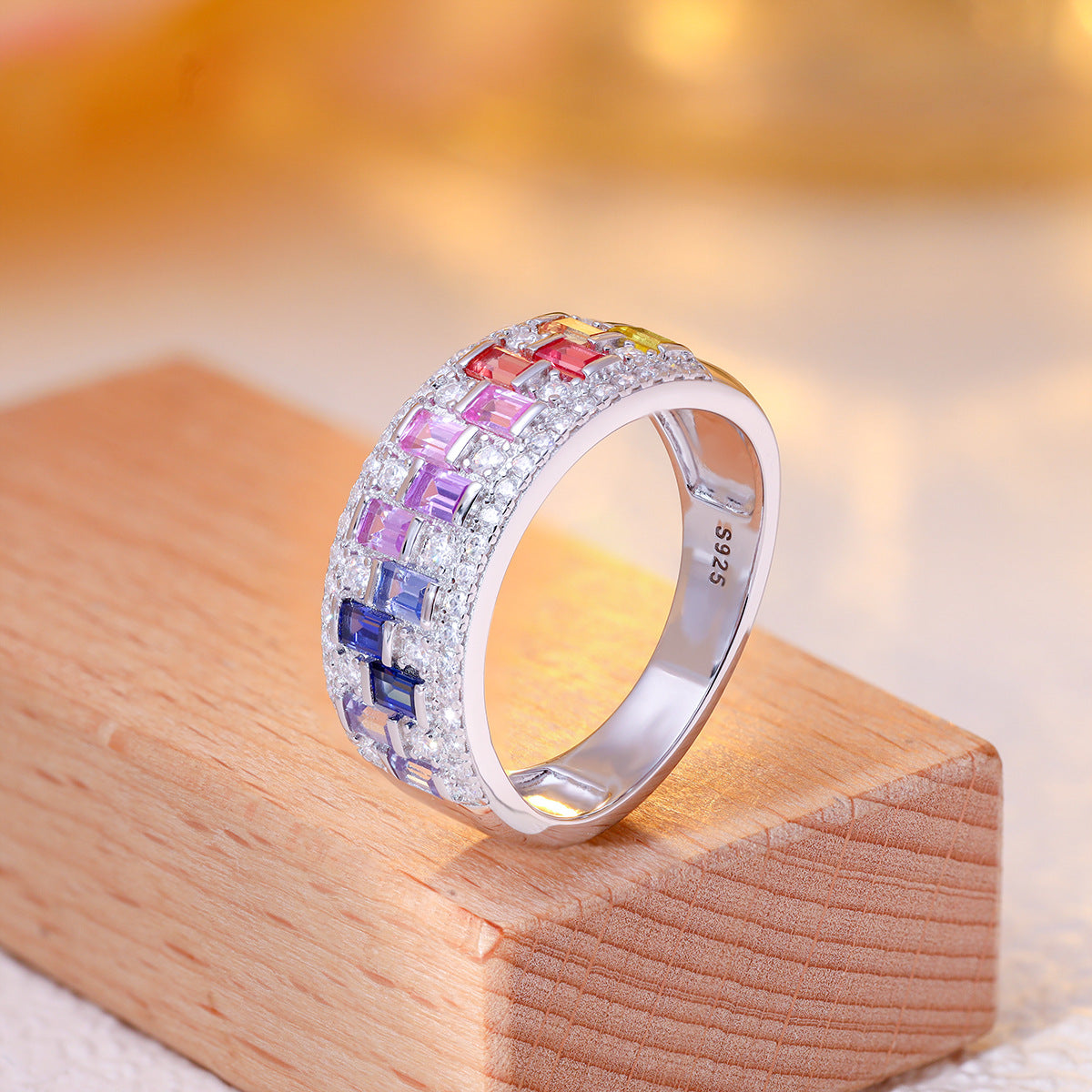 Multicolor baguette gemstone and moissanite wide band ring in sterling silver on wooden block
