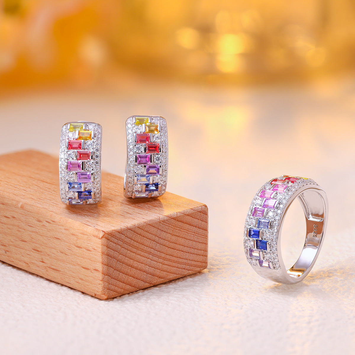 Group display of multicolor baguette gemstone and moissanite wide huggie hoop earrings and matching ring