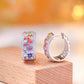 Angled view showing clasp of multicolor baguette gemstone and moissanite wide huggie earrings