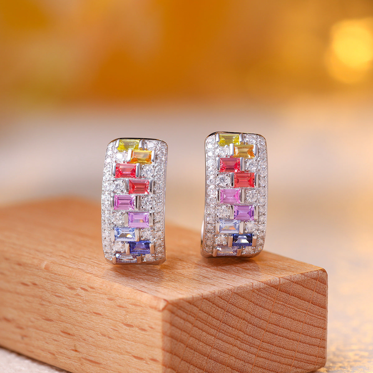 Multicolor baguette gemstone and moissanite wide huggie hoop earrings on wooden stand