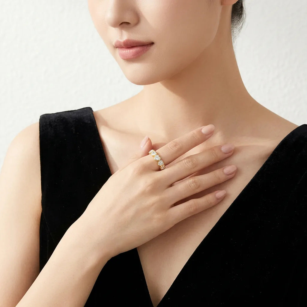 Elegant lifestyle wear shot of a model styling an old money aesthetic graduated heart gemstone eternity band in a gold tone.