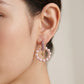 Close up lifestyle view of a model showcasing old money aesthetic moondance pearl drop earrings with logo charms.