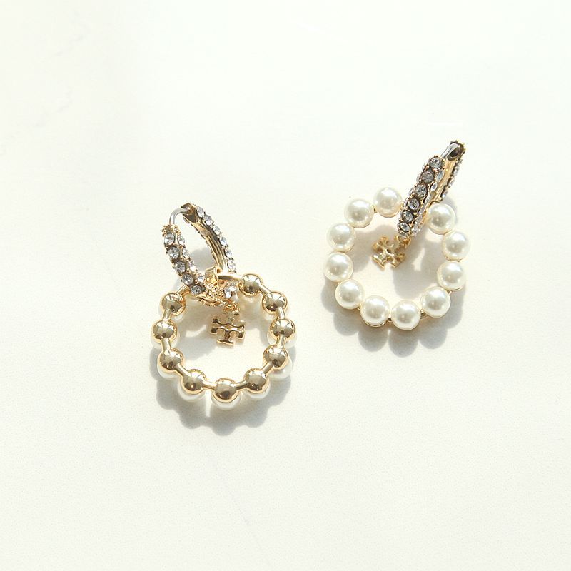 Studio flat lay of old money aesthetic moondance white pearl hoop earrings with delicate gold logo charms underneath light.
