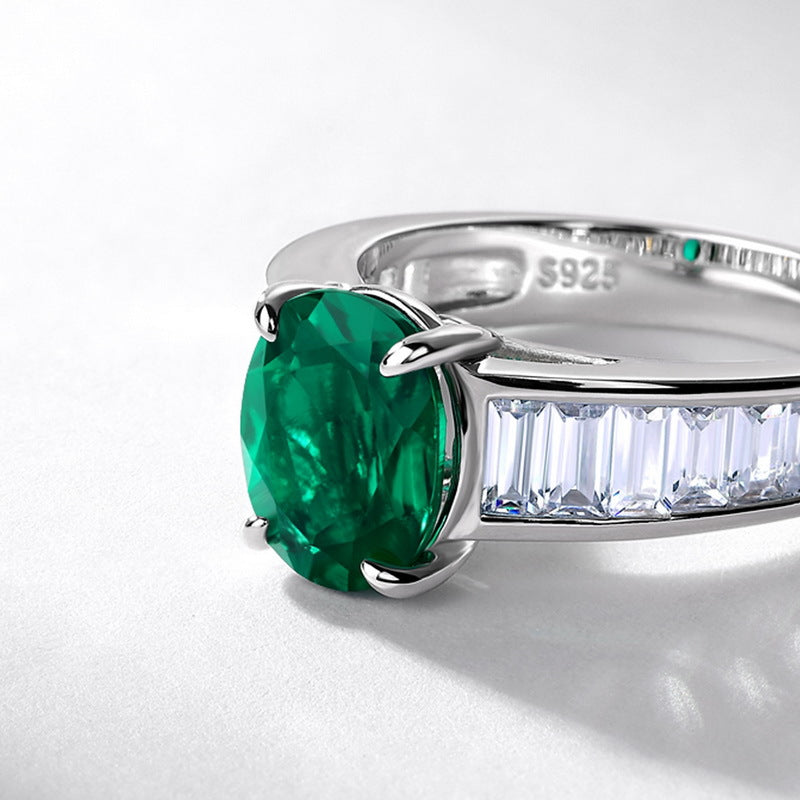 Silver ring with a green gemstone and diamond accents on a white background