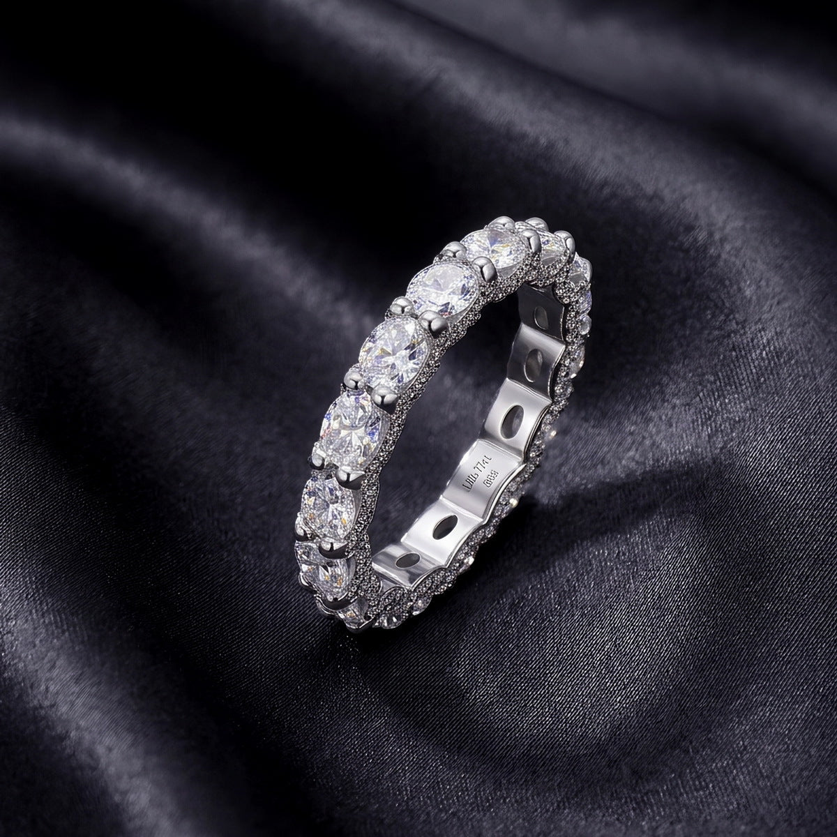 Angled profile view of oval cut lab-grown diamond eternity band ring on dark silk.