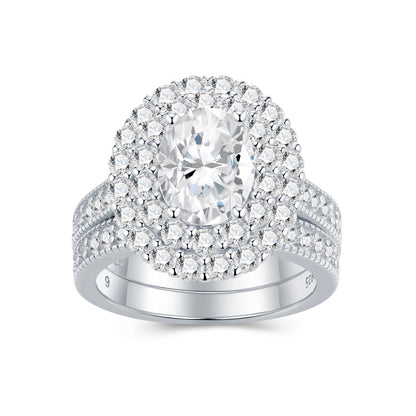 Oval cut moissanite double halo bridal ring set with matching milgrain wedding band on white background.