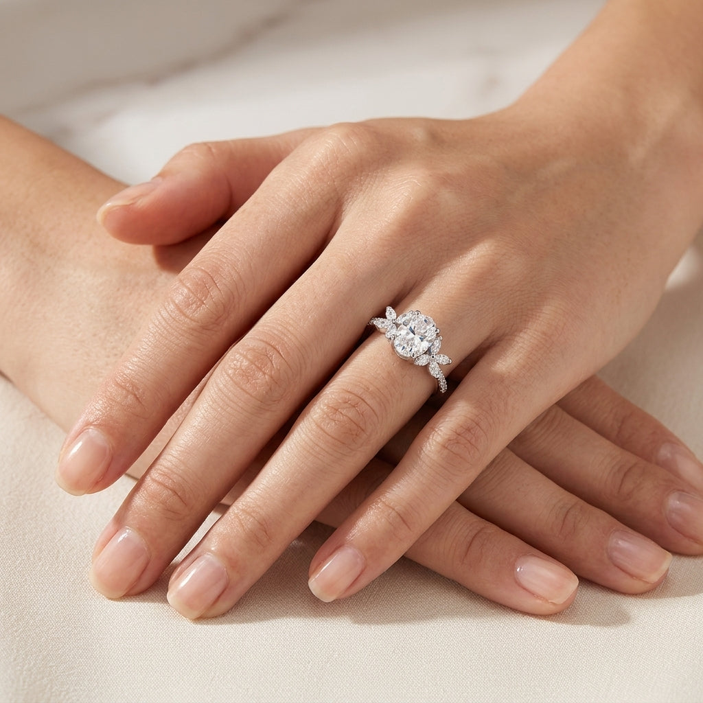 Editorial fashion lookbook portrait of an oval moissanite engagement ring with marquise leaf cluster accents styled on hand.