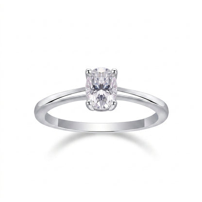 Oval cut moissanite solitaire engagement ring with dainty plain silver band on white background.
