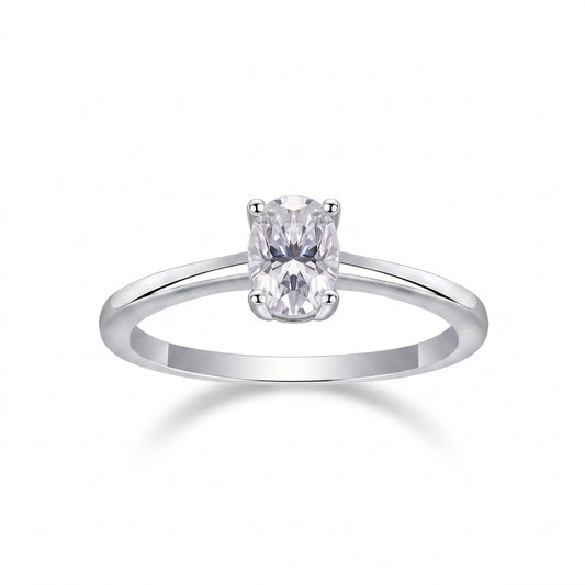 Oval cut moissanite solitaire engagement ring with dainty plain silver band on white background.