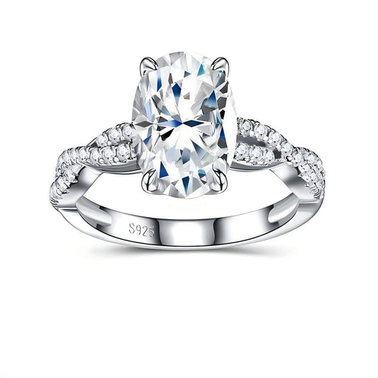 Oval cut moissanite engagement ring with pave twisted vine infinity band on white background.