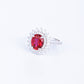 Side profile view of a pair of ruby Diana halo stud earrings on display steps.