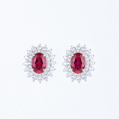 Classic oval-cut ruby Diana halo stud earrings in brilliant sterling silver cluster setting.