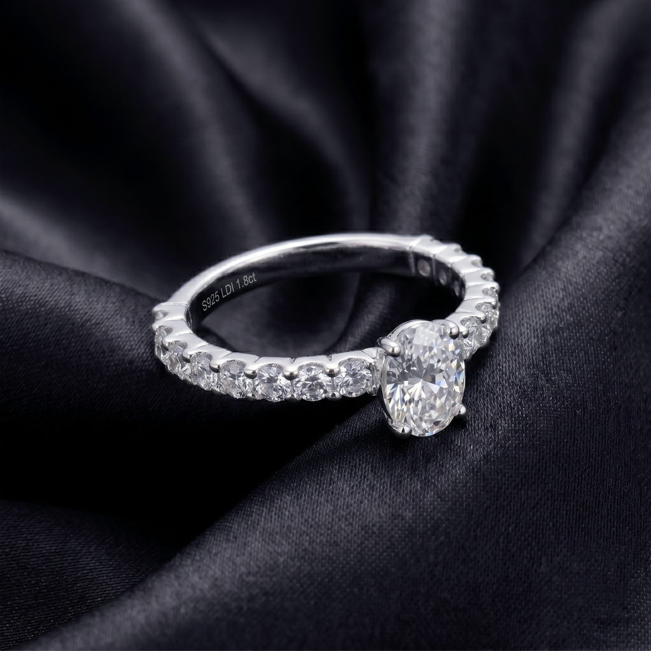 Perspective view of oval lab grown diamond pave engagement ring resting on dark silk.