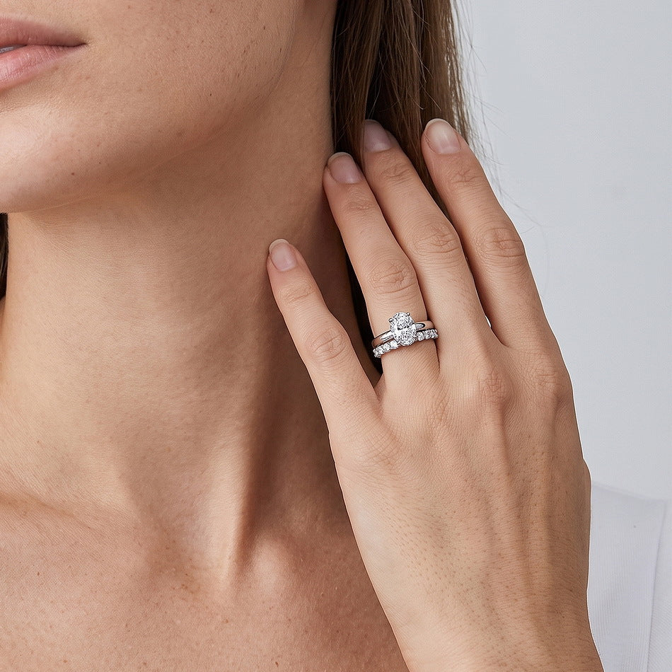 Angled perspective shot of oval engagement ring stacked with curved pave accent wedding band.