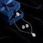 Oval lab diamond four-prong pendant necklace with matching ring and stud earrings set on dark blue velvet box   