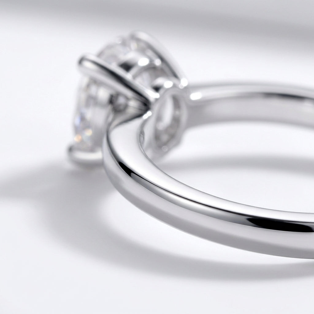 Macro side profile showing 4-prong basket setting and polished shank on oval moissanite ring.