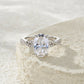 Oval cut moissanite infinity ring resting on textured stone surface.