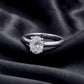 Angled top view of oval cut lab grown diamond plain solitaire ring resting on dark silk.