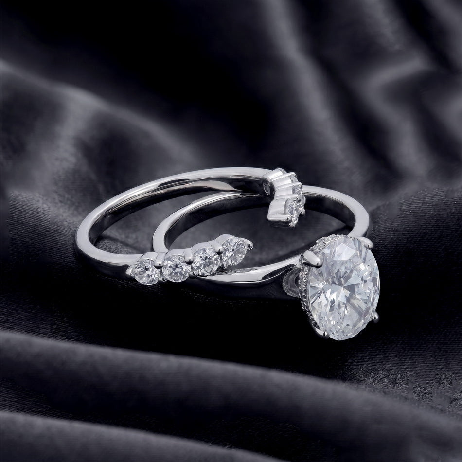 Oval solitaire engagement ring and matching curved pave wedding band shown separated on dark silk.