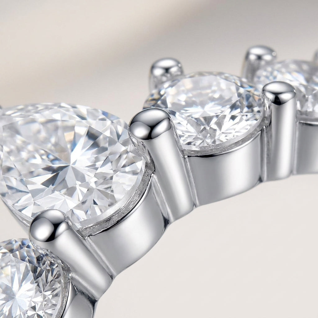 Macro close-up showing prong-set pear and round moissanite stones on silver tiara ring.