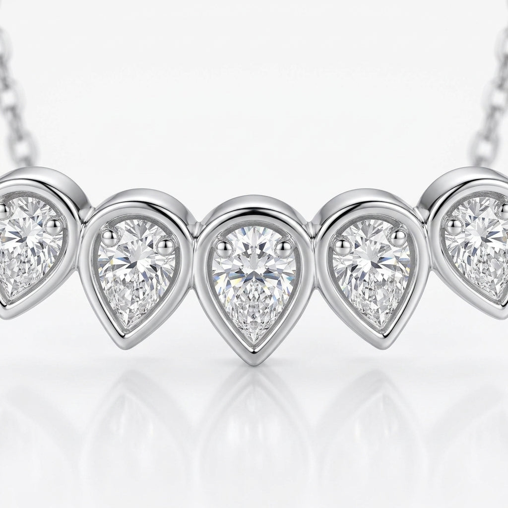 Close-up view of bezel set graduated pear cut moissanite teardrop bar pendant.