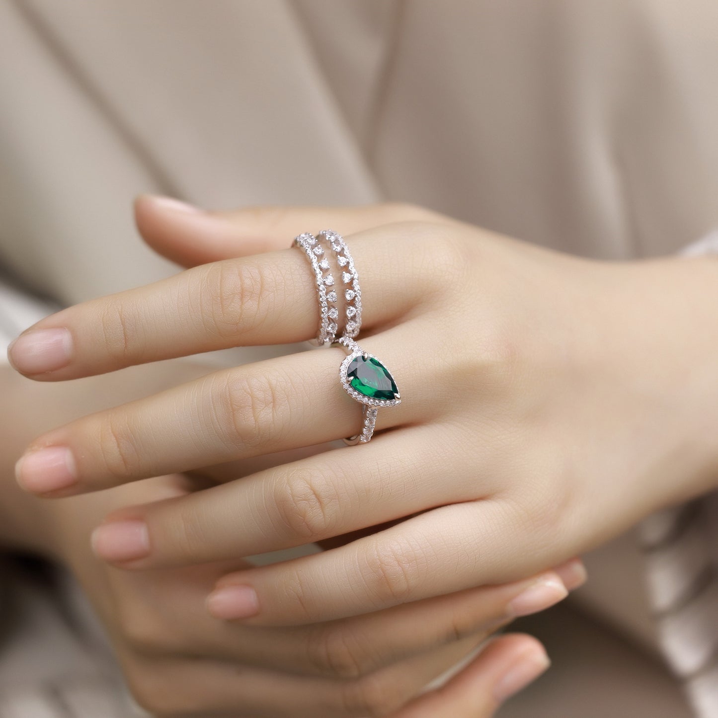 Elegant model showing a luxury pear-cut emerald stackable ring set for women styled on her finger.