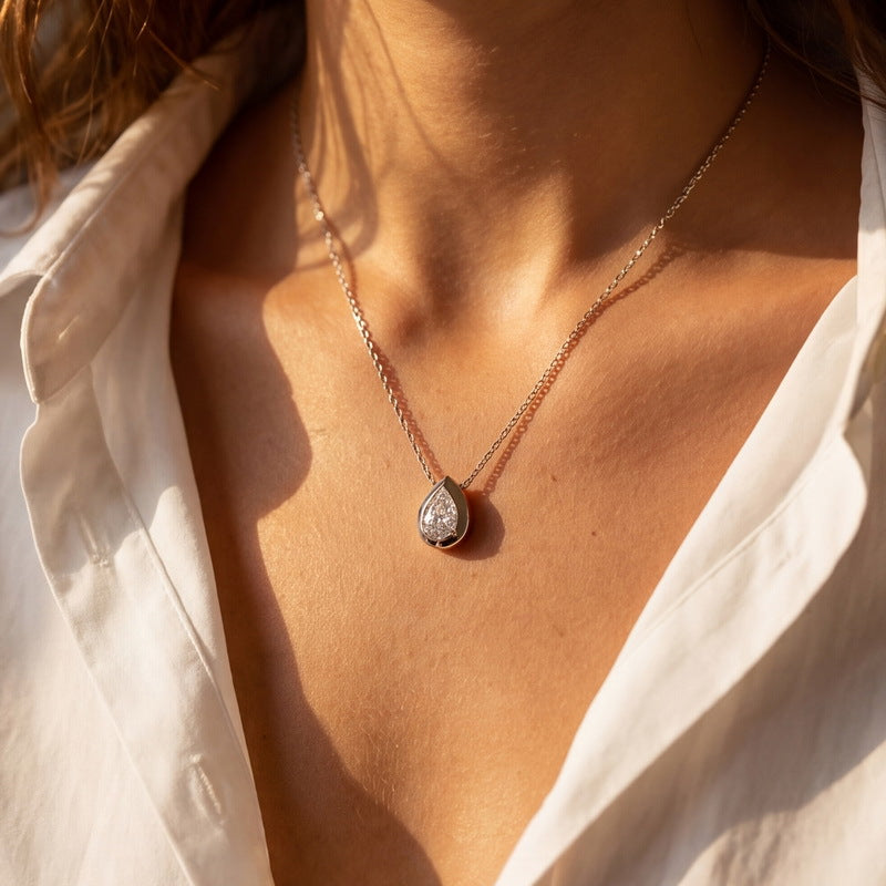 Model showing pear cut lab grown diamond faceted bezel necklace in natural sunlight.