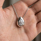 Hand holding pear cut lab grown diamond pendant showing thick faceted bezel architecture.