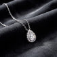 Perspective view of pear cut lab diamond halo teardrop pendant necklace resting on dark silk.