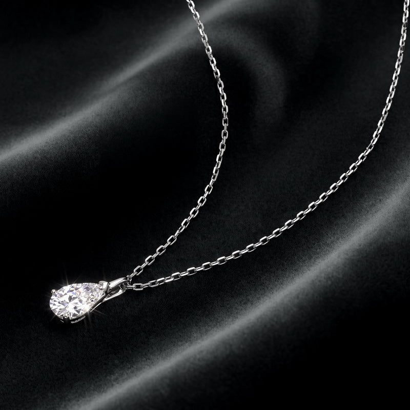 Perspective view of pear cut lab diamond teardrop pendant necklace resting vertically on dark silk.
