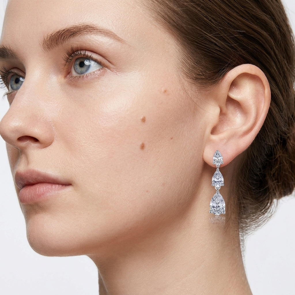 Model wearing pear cut lab grown diamond linear dangle drop earrings.
