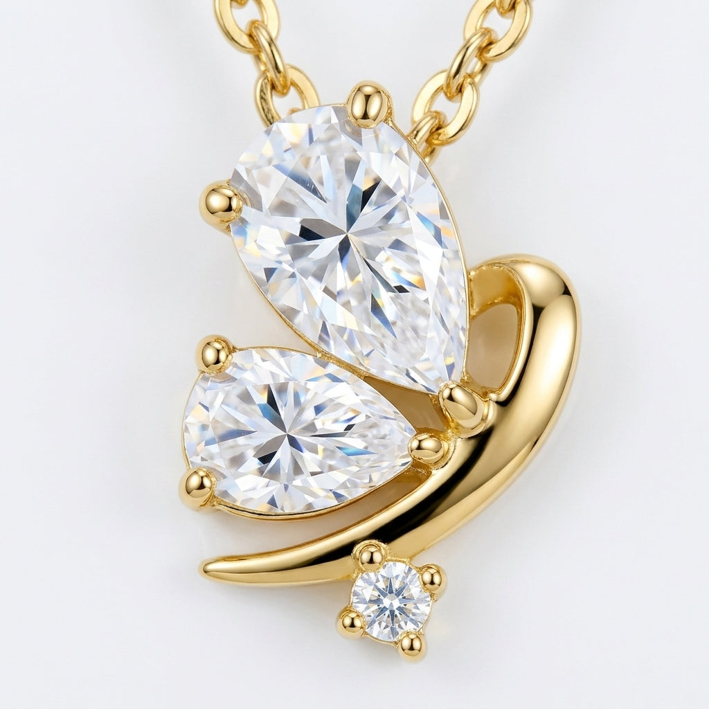 Macro close-up showing two pear-cut moissanite wings and fluid gold curve on butterfly pendant.